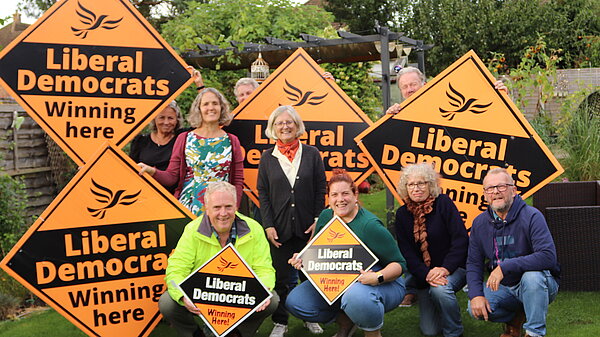 Group of people in a garden with Lib Dem Plackards